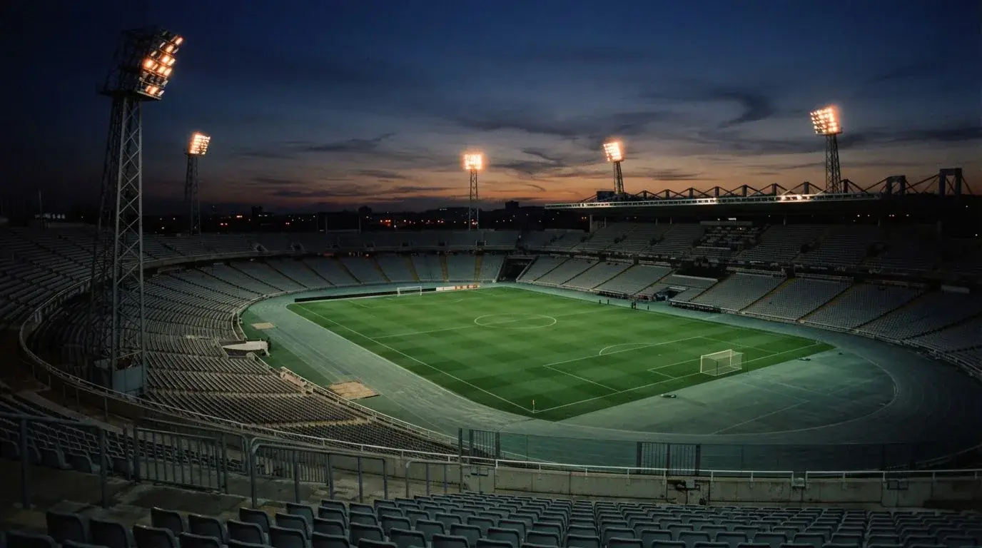 An empty football stadium with floodlight masts at dusk