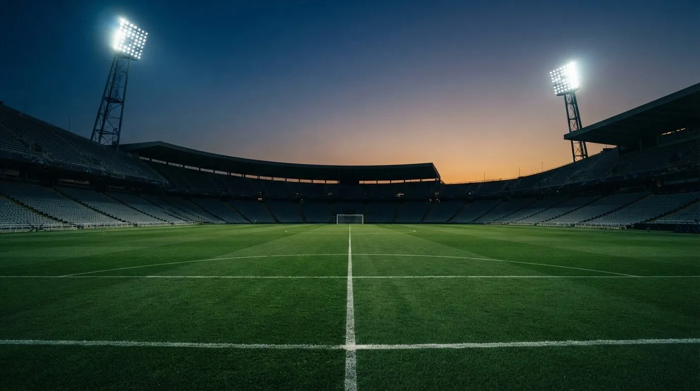 An empty football stadium with floodlight masts at dusk